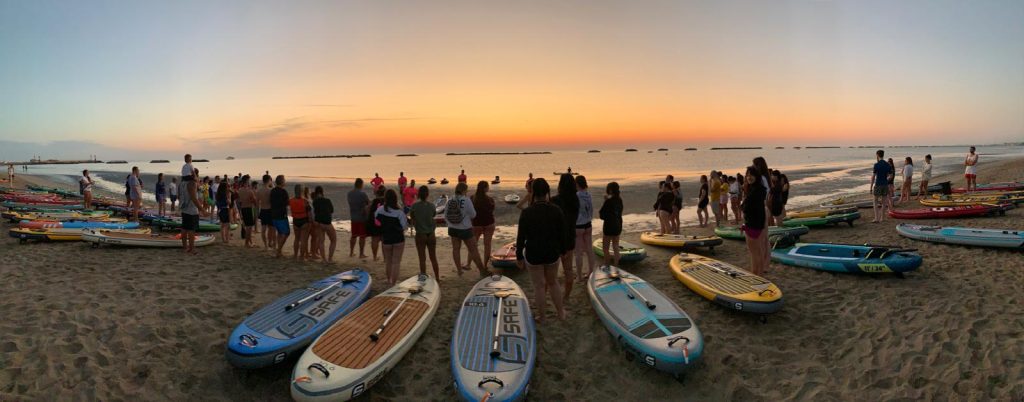 Panoramica dei Giovani Soci RomagnaBanca con le tavole SUP sulla spiaggia di Cesenatico all'alba