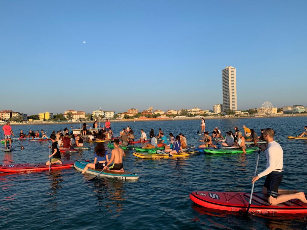Giovani Soci RomagnaBanca rientrano verso la costa di Cesenatico dopo l'alba in Sup, con lo skyline sullo sfondo