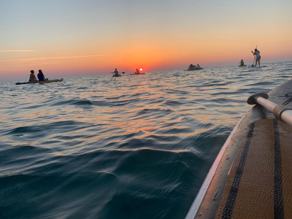 Il sole sorge sull'orizzonte visto dalle tavole SUP dei Giovani Soci RomagnaBanca a Cesenatico