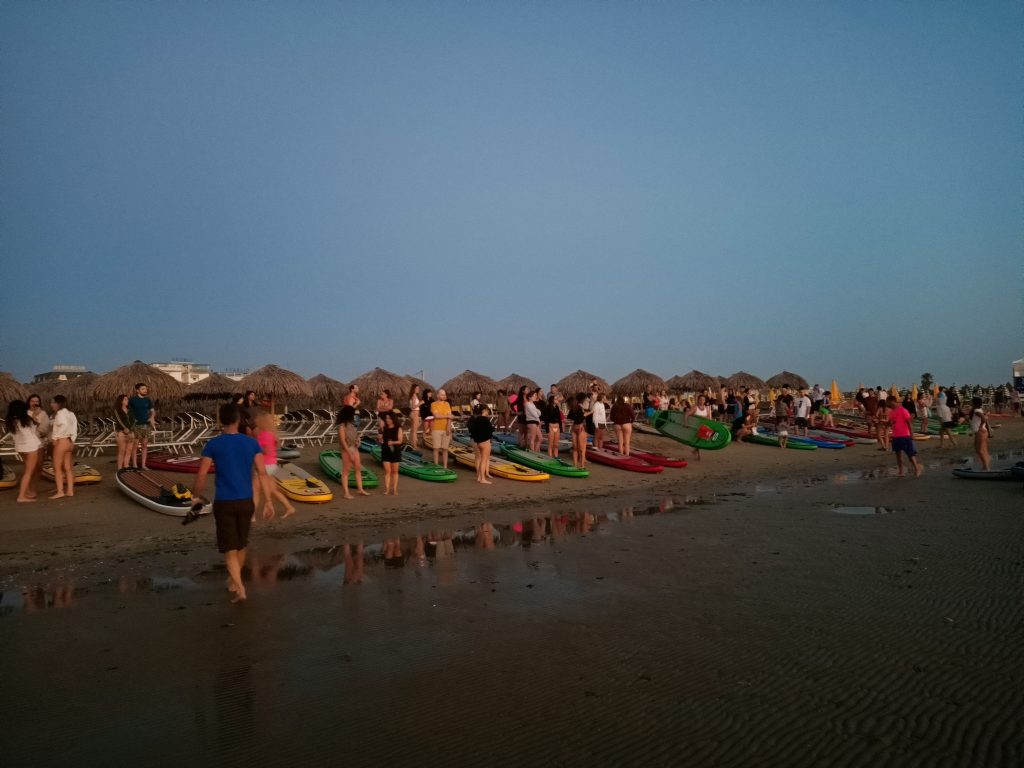 Giovani Soci RomagnaBanca tra le tavole SUP sulla spiaggia di Cesenatico nella luce dell'alba
