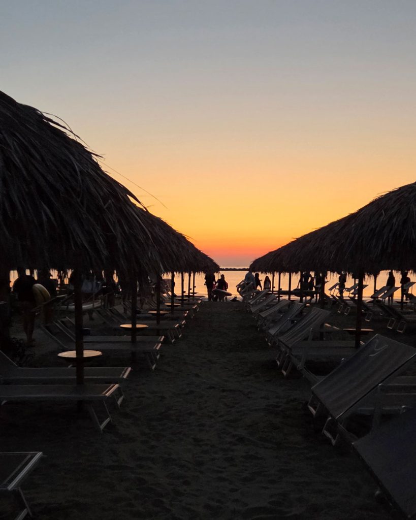 L'alba si accende tra gli ombrelloni del Bagno Cala Romeo durante l'alba in Sup dei Giovani Soci RomagnaBanca