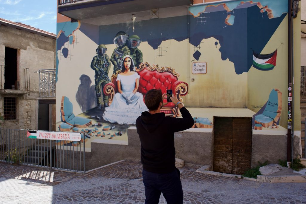 Giovane Socio fotografa un murale ad Aielli nella visita al termine del 16° Forum nazionale