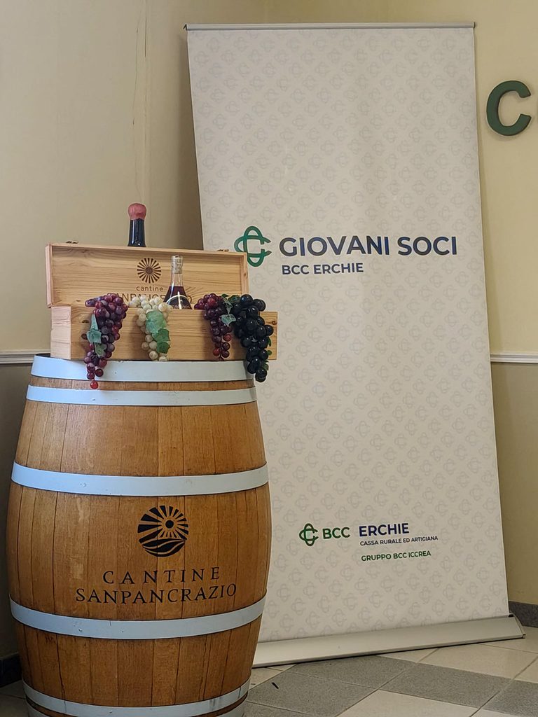Il logo dei Giovani Soci BCC Erchie accanto a una botte delle Cantine San Pancrazio